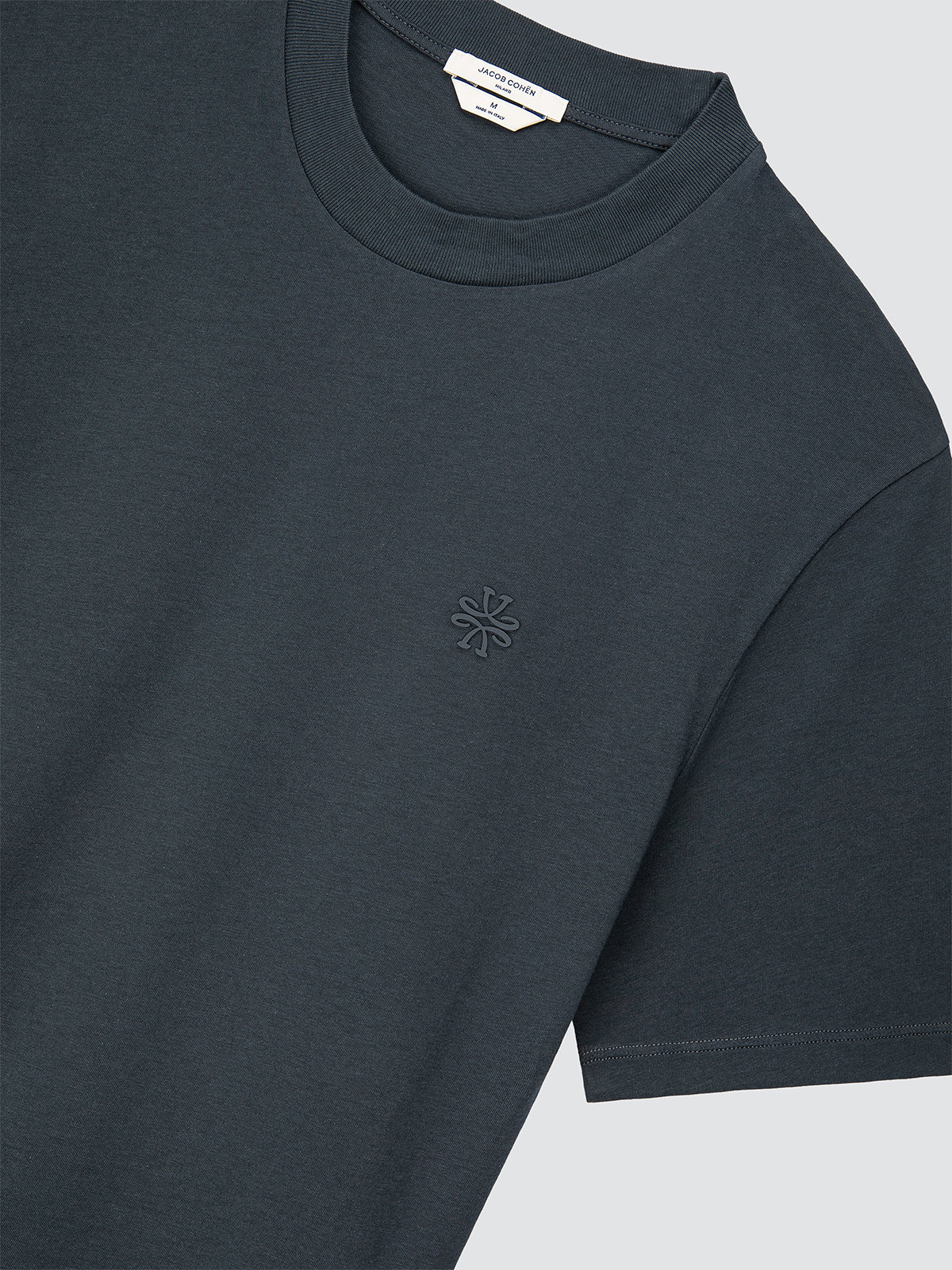 Navy blue t-shirt with a small logo on a light gray background