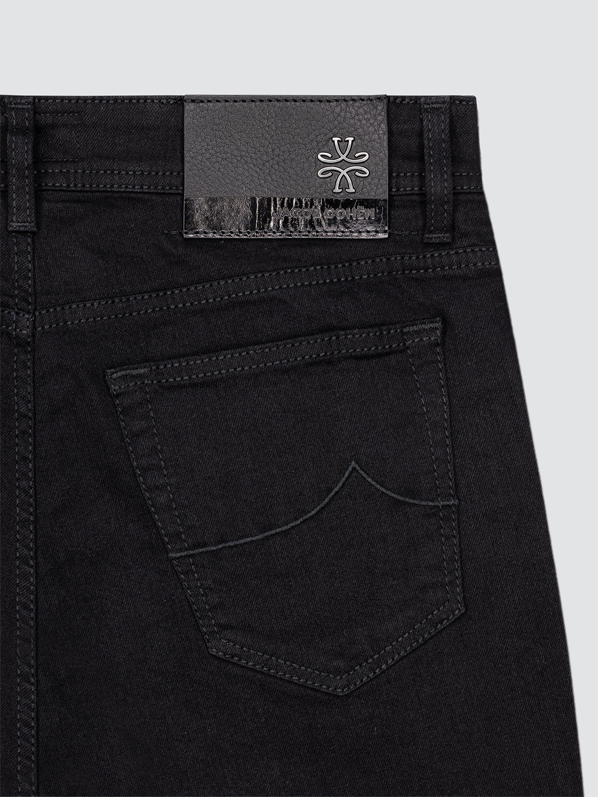 Close-up of black jeans Jacob Cohën brand Bard with a brand label on a light gray background