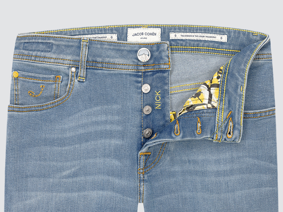 Close-up of blue jeans with brand labels on a light gray background