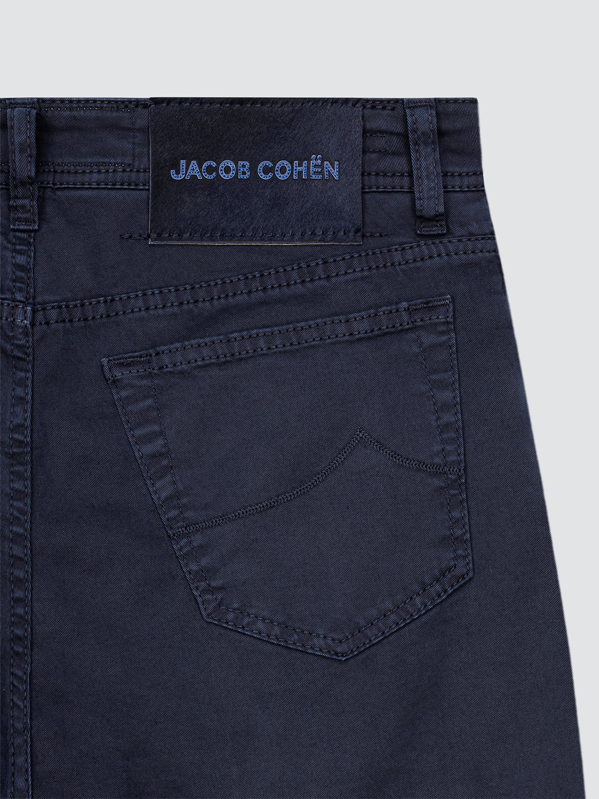 Navy blue pants with 'JACOB COHEN' branding on a light gray background