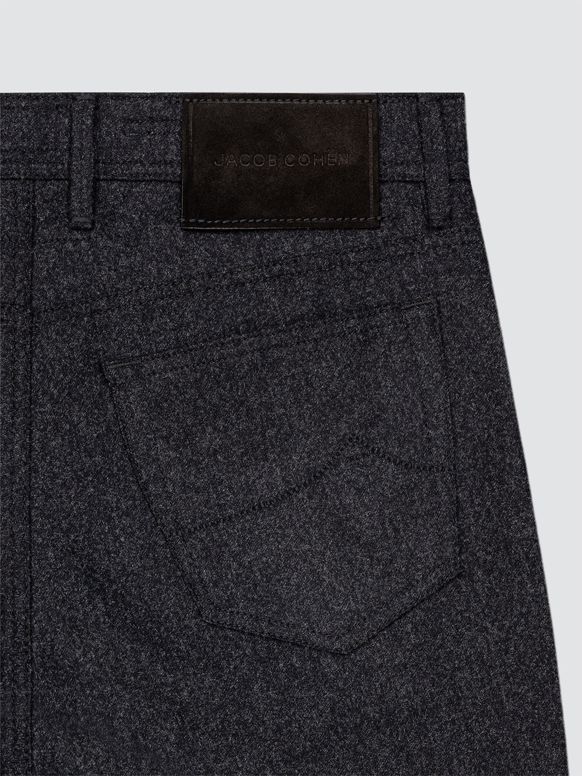 Dark gray pants with a brand label Jacob Cohen on a light gray background