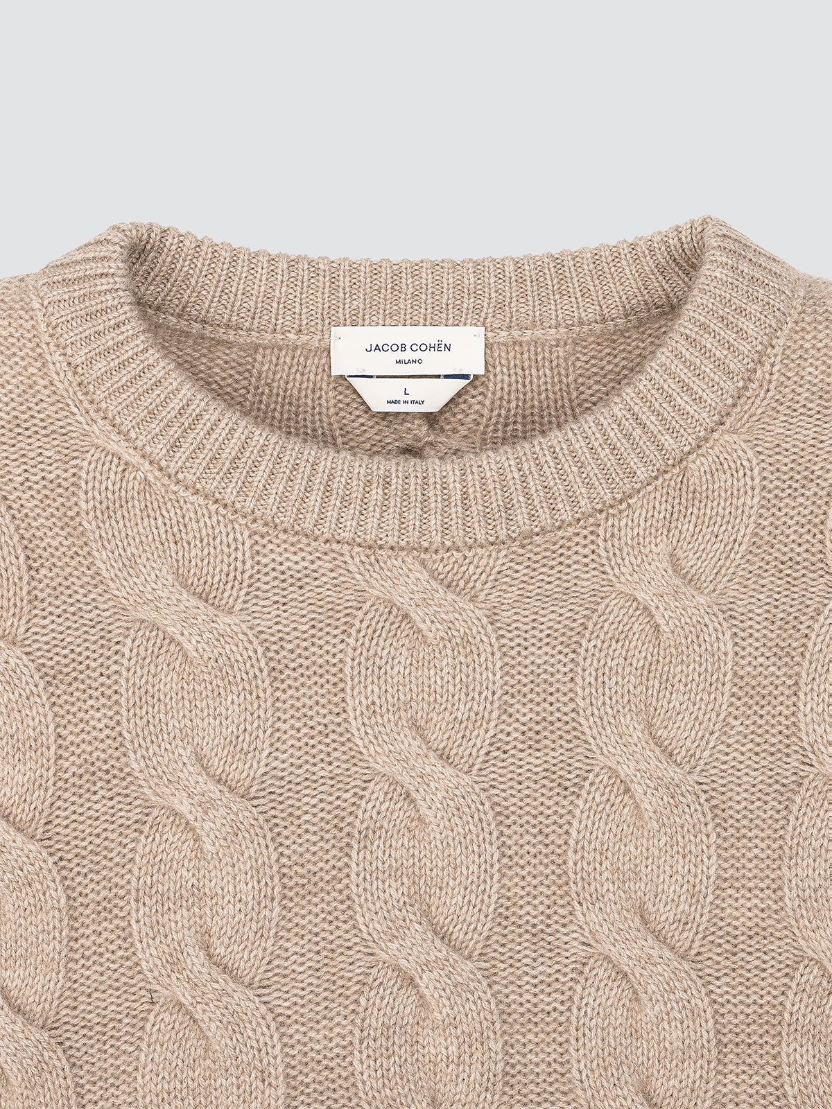 Close-up of a beige cable knit sweater in cashmere with 'Loro piana' label.